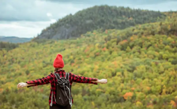 Female hiker in the mountains on a fall day with vibrant fall trees.