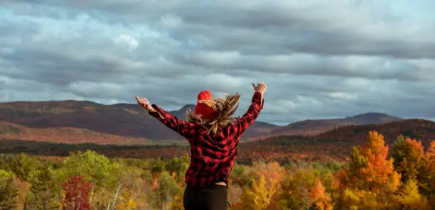 Female hiker in the mountains on a fall day with vibrant fall trees.