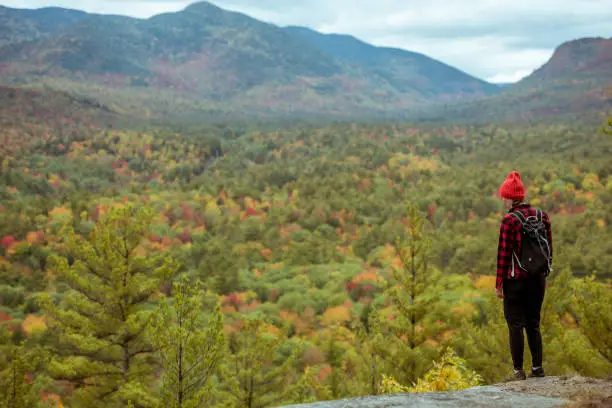 Female hiker in the mountains on a fall day with vibrant fall trees.