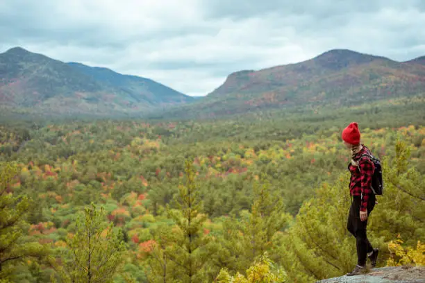 Female hiker in the mountains on a fall day with vibrant fall trees.