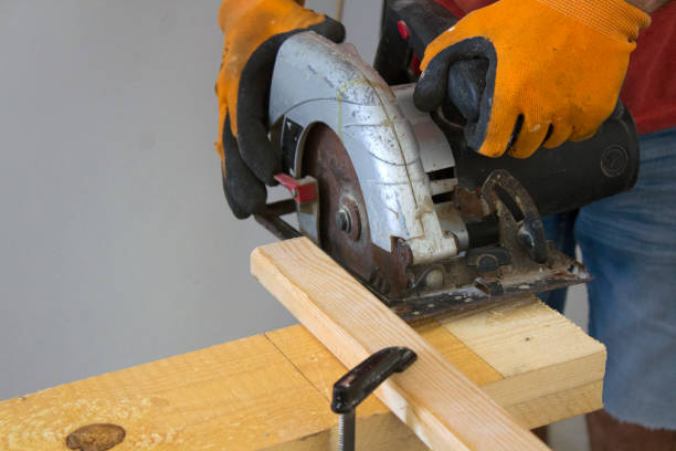 istock Man in orange protective gloves holds circular saw. 1277649911