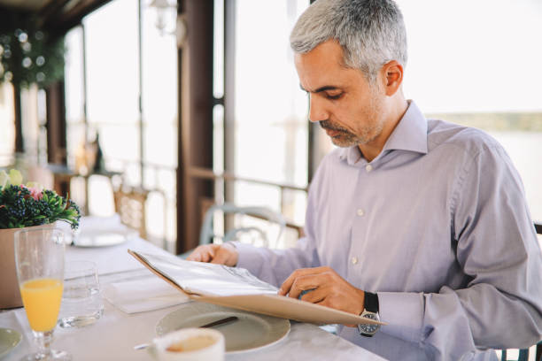 istock Mid aged man looking at the restaurant menu 1277652766