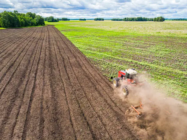 Aerial view drone of harvest field with tractor mows dry grass. Autumn yellow field with a haystack after harvest top view. Harvesting in the fields. Stock up on hay for the winter. Top view