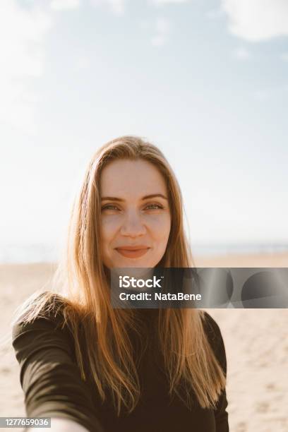 Foto de Retrato De Mulher Bonita Com Cabelo Comprido Loira Tira Selfie No Celular Em Praia De Areia e mais fotos de stock de Selfie