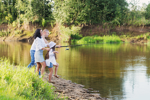 happy family with fishing rod on summer river