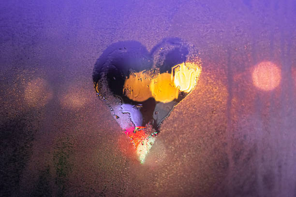 Close-up drawn heart on a foggy wet window