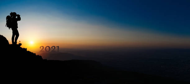 A man climbed a mountain peak, looking binoculars to the new year