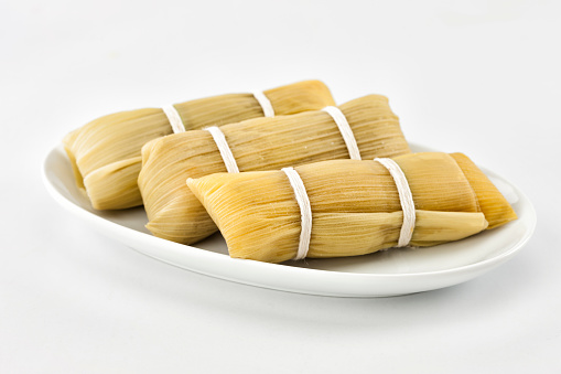 Homemade tamales wrapped in dry corn leaves. Tamales are a traditional dish from Mexico and from many other Latin American countries, usually stuffed with beef, chicken or pork stew.
