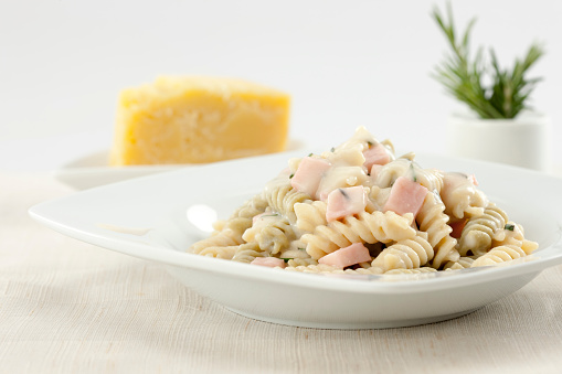 Creamy cheese and ham pasta, with parmesan and rosemary. Sparse composition.