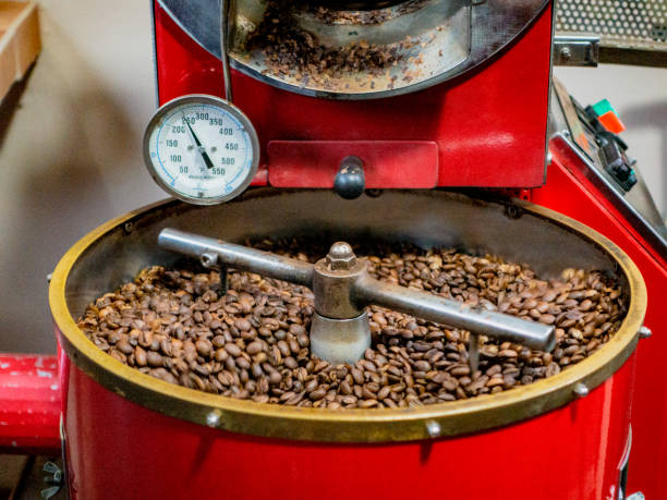 los granos de café son agitados por la máquina, ya que se cocinan en preparación para embolsarse - roasted machine bean mixing fotografías e imágenes de stock