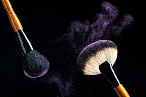 istock Makeup concept with a  professional makeup brushes with glowing purple eye shadow isolated on black background. 1277666002
