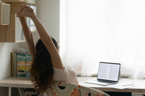 Young woman stretch in chair working on laptop