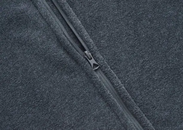 Closeup of a black zipper on a black fleece coat.