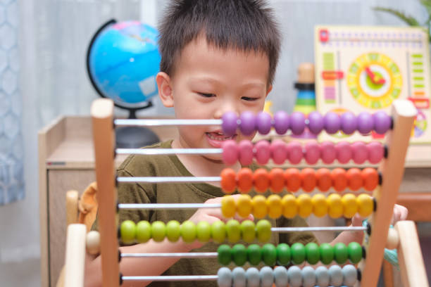istock Cute little asian kindergarten 4 years old boy sitting on floor using the abacus with beads to learn how to count indoor at home 1277680168