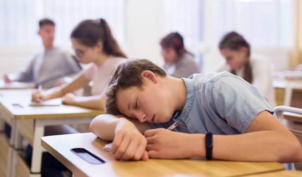 istock Tired bored teenage school boy sleeping at desk 1277681784