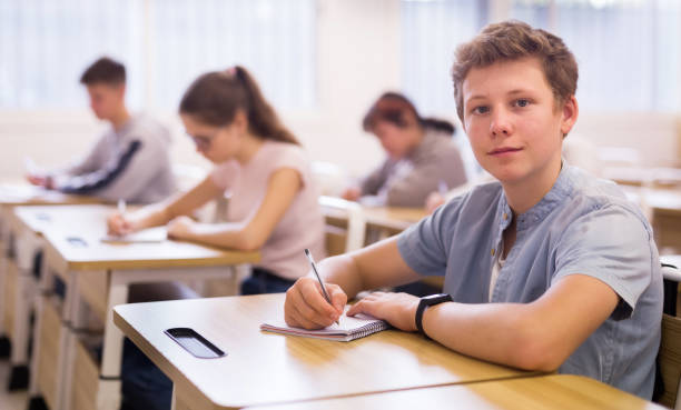 istock Teen boy sitting at desk in classroom 1277681785