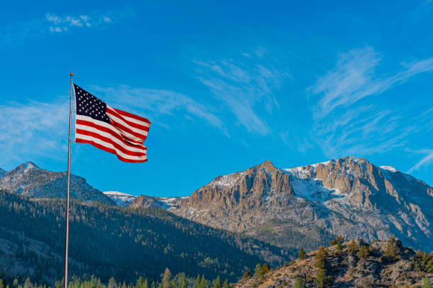 Gull Lake in California flies an American flag above the lake. An American flag flies over the Californian Sierra Nevada mountains in the Gull Lake area of California. The lake area is on the June Lake Loop. foothills photos stock pictures, royalty-free photos & images