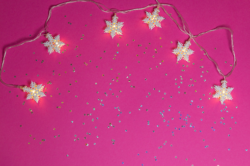 Stars garland on pink background with glittered little stars. Christmas theme with space for text writing, greeting. Concept banner for Christmas card, advertising. Top view. High quality photo