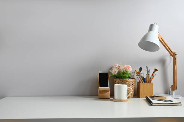 istock Minimal worktable with coffee cup, plant, lamp, office supplies and copy space with in modern home office. 1277705032
