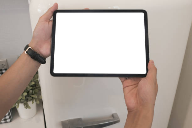 istock Mock up image of hand holding digital tablet with white screen in kitchen. 1277705132