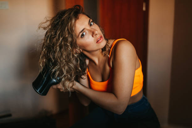 Young woman dries her hair with hairdryer stock photo