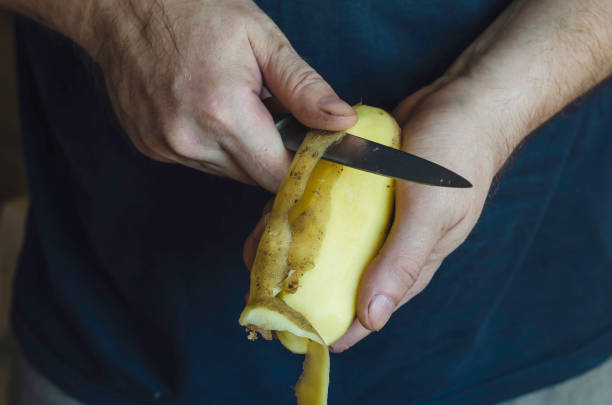 istock A mature man peels raw potatoes with a kitchen knife. 1277706820