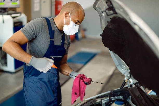 black auto mechanic checking car oil while wearing face mask in repair shop. - lubrication infection imagens e fotografias de stock