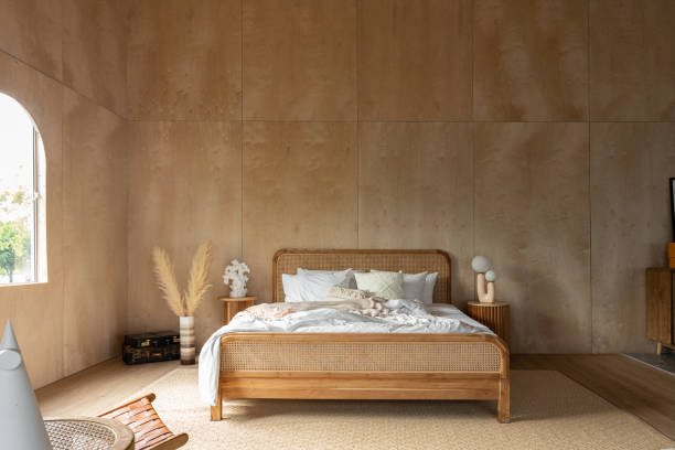 istock Stylish Bedroom corner with rattan headboard and bed with soft pillows setting with white pillows plywood wall on the background / cozy interior design / modern interior 1277715781