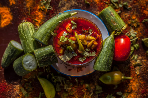 close up shot of gujarati famous galka nu shaak on a glass plate. shot of sponge gourd dish in a glass plate along with all the spices on a brown with some fresh tomatoes and sponge gourd. - asia cooked food gourmet imagens e fotografias de stock