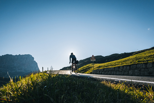 Road biker ascends mountain road in the morning