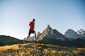Trail runner traverses alpine meadow at sunrise
