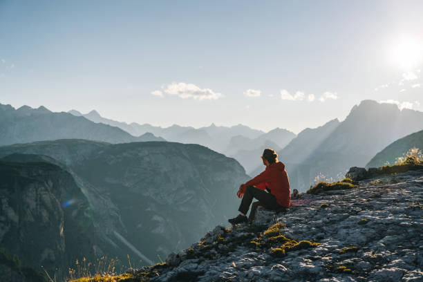 Hiker relaxes on mountain ridge at sunrise