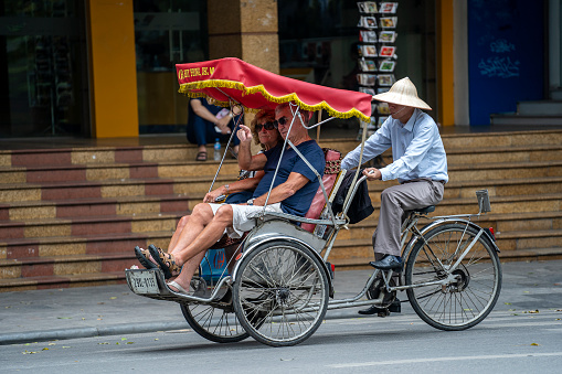 Hanoi, Vietnam - march 01, 2020 : Vietnamese rickshaw driver with tourists on street in old town Hanoi, Vietnam