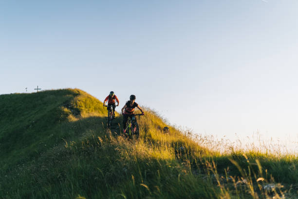 istock Mountain bikers ride down grassy mountain ridge 1277729342