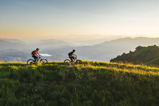 Los ciclistas de montaña andan a lo largo de la cresta de la montaña cubierta de hierba photo