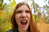 Portrait of crazy screaming young woman. The red-haired girl with her mouth open and screams. Emotional girl. Angry girl