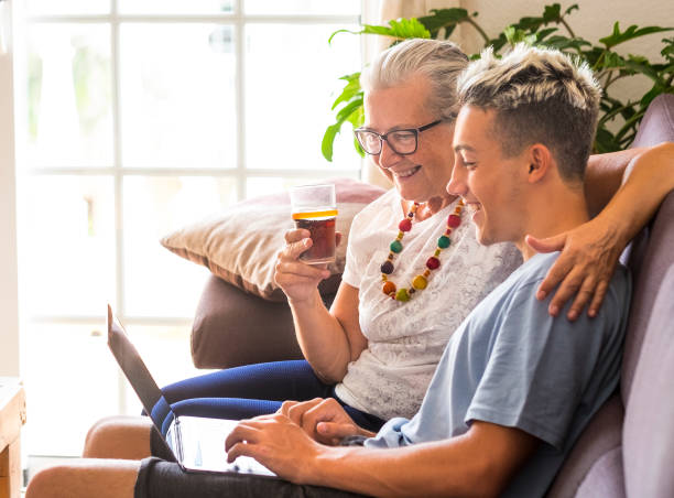 istock The old and new generation of millennials share the same laptop while having fun.  Grandson teaches grandmother how to surf the Internet. Teen and senior smile happily, concept of love and friendship 1277730962