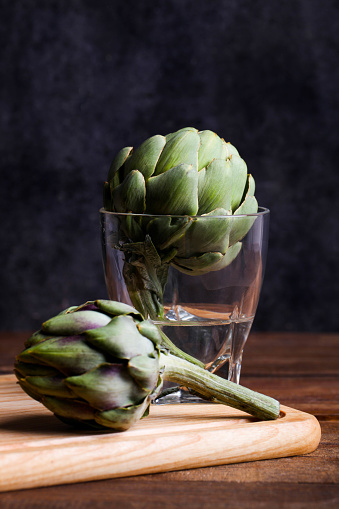 Two fresh artichokes in a glass of water.