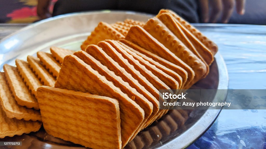 Wheat biscuits in the steel plate with blury background. Indian biscuits popularly known as Chai-biscuit in India Accessibility Stock Photo