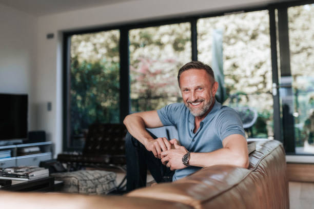 istock portrait of smiling relaxed handsome midaged man sitting on leather sofa 1277733073