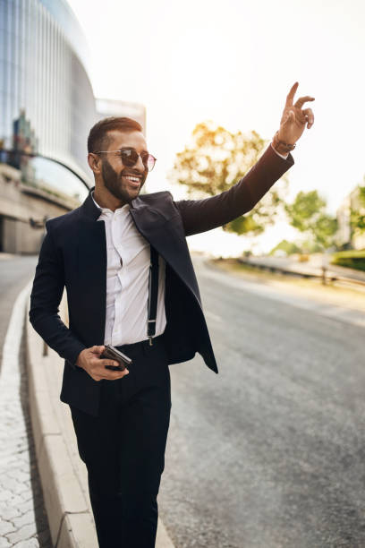 istock Dapper Indian Arabic businessman waving down taxi cab e-hailing 1277733135