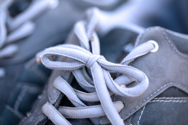 Shoes tied together on lilac background. April Fool's Day