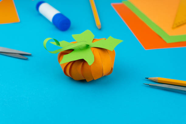 istock Step 9. Step by step instructions on how to make a pumpkin from colored paper or cardboard. Do it yourself. Glue, a ruler, compasses, scissors. A DIY craft for children. Decoration for the Halloween 1277735989