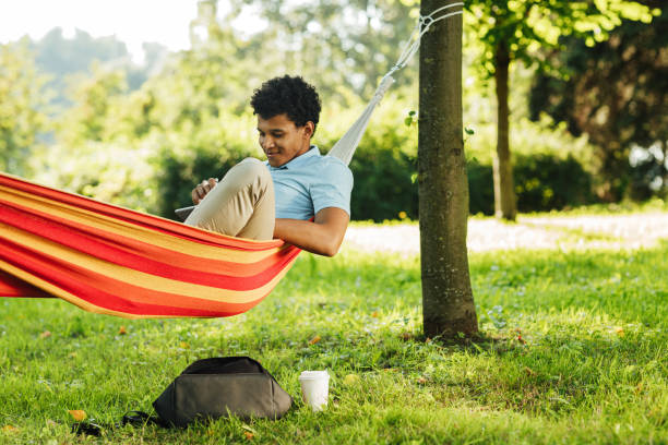 istock Young man wearing casuals resting on a hammock in park 1277738769