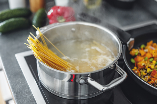 Boiling pot with cooking spaghetti pasta in the kitchen. Closeup