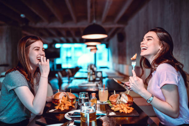 istock Smiling Female Friends Enjoying Special Burger Dinner 1277748622