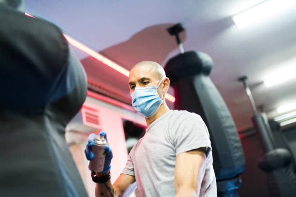 istock Man sprays disinfectant on punch bag at gym 1277753718