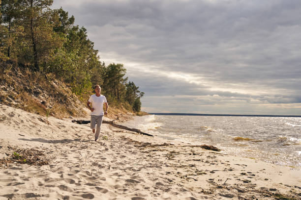 해변에서 아침에 달리는 행복한 남자 - relaxation muscular build simple living rural scene 뉴스 사진 이미지