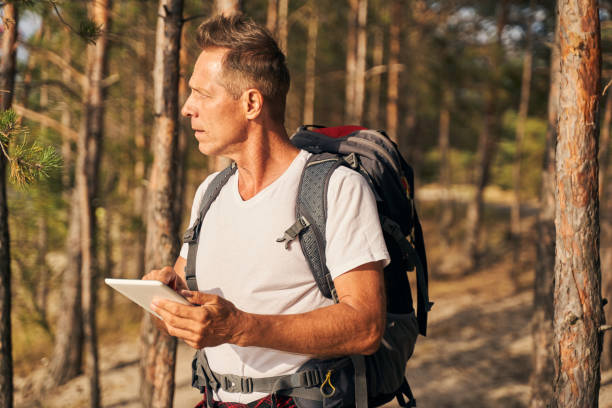 istock Sporty man going hiking with tablet in wood 1277754114
