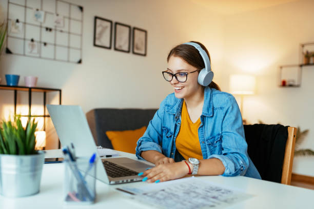 Smiling woman using headphones during online webinar or video call stock photo